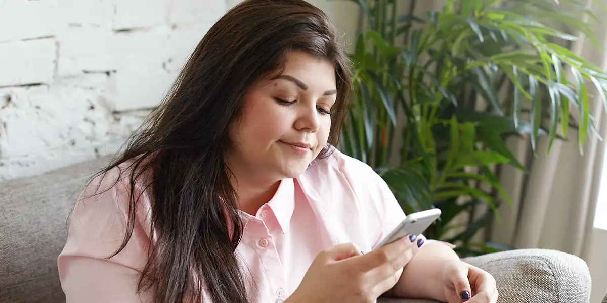 Indoor shot of overweight young dark haired female in pink shirt consulting with doctor -tablet