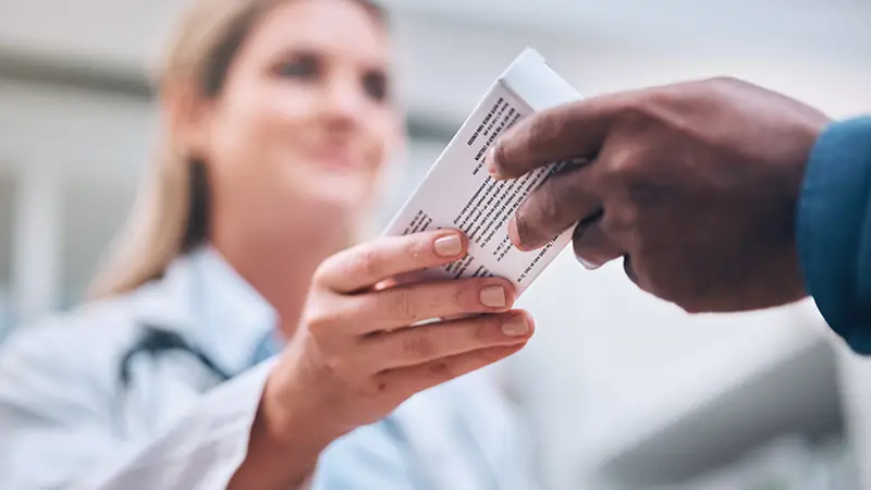 pharmacist handing glp-1s medication to patient in pharmacy