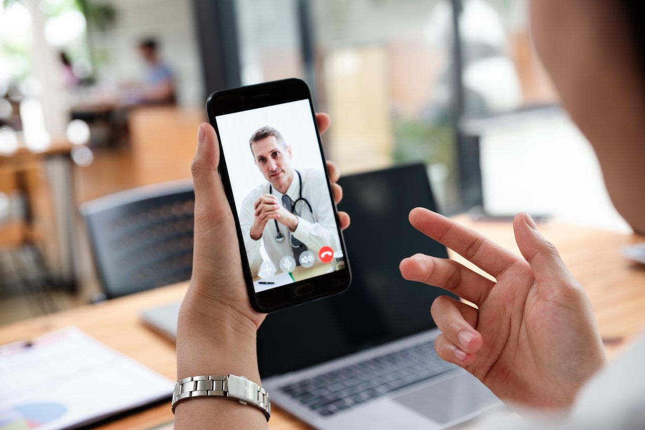 Young woman meeting her doctor via video call by smart phone at home